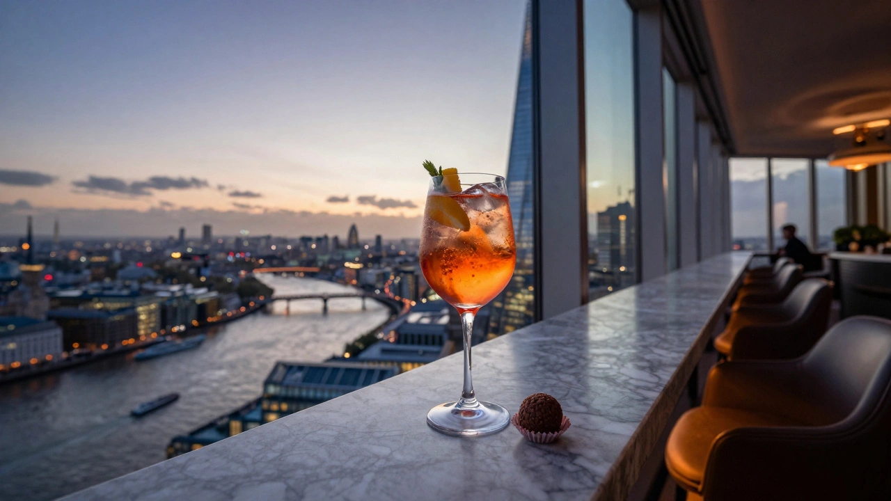 A glass of spritz with chocolate truffle on The Shard’s rooftop overlooking London at dusk.
