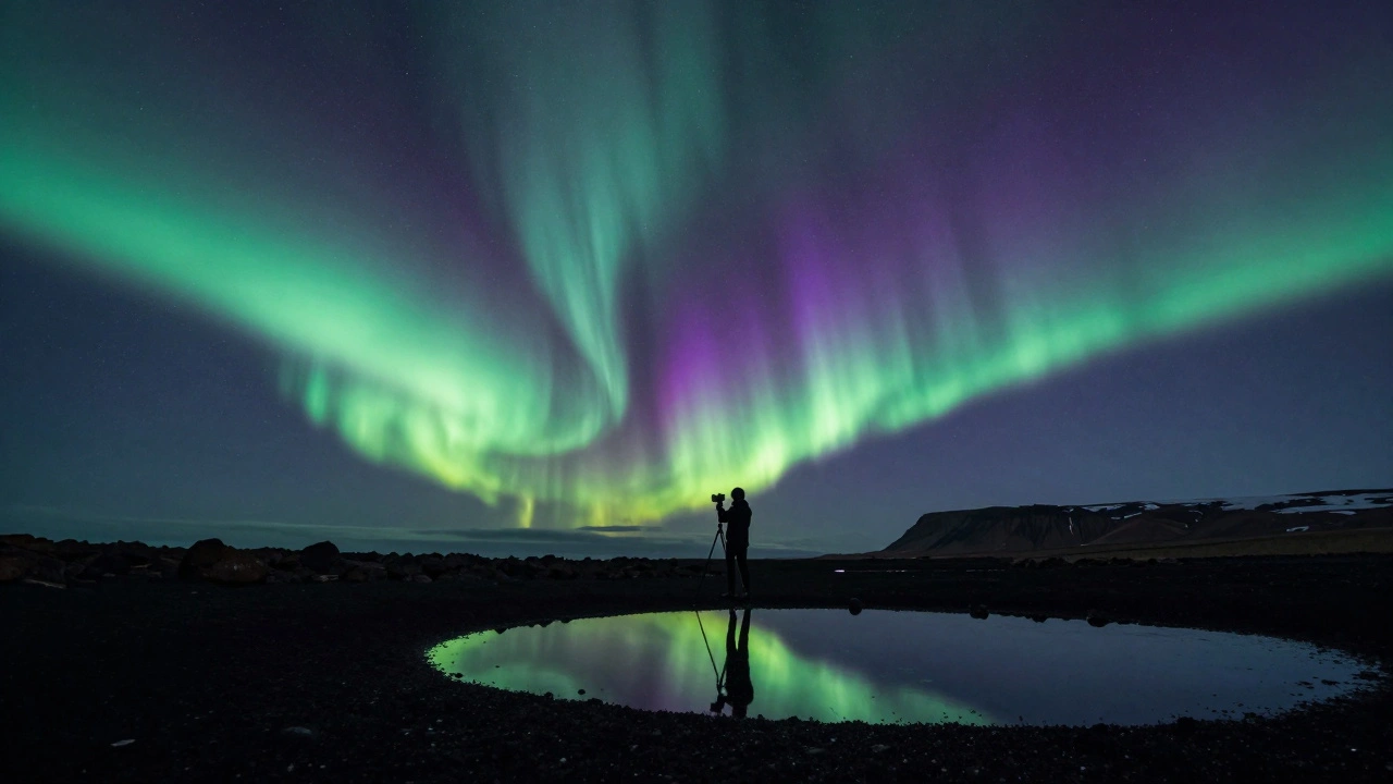 Solitary figure under swirling northern lights on an Icelandic shore, tripod in foreground.
